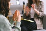 Crop anonymous female psychologist in smart casual clothes calming lady during appointment in modern office