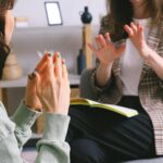 Crop anonymous female psychologist in smart casual clothes calming lady during appointment in modern office